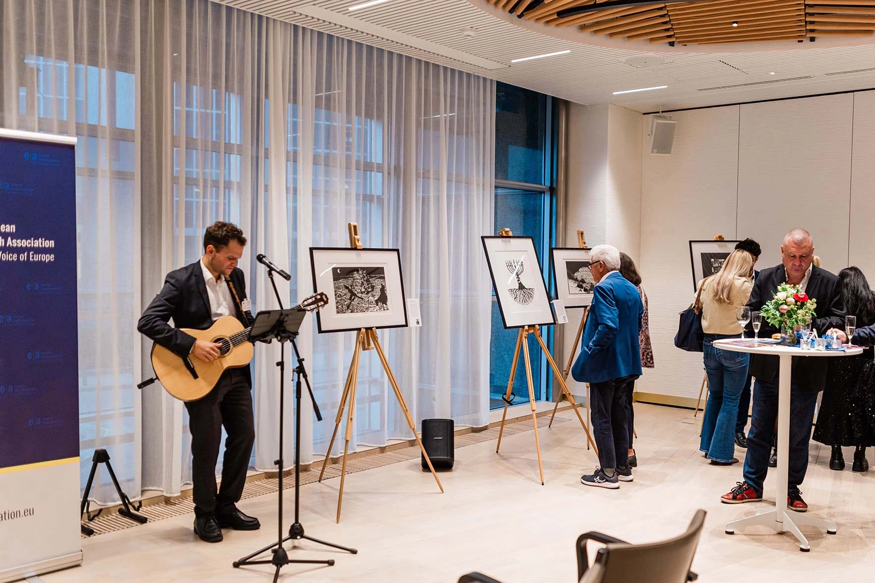 Musician performing beside the exhibited lithographs