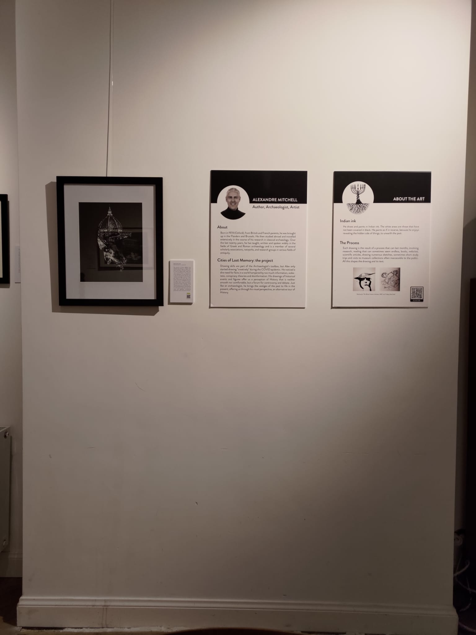 Artist and process panels beside a framed work at Full Circle